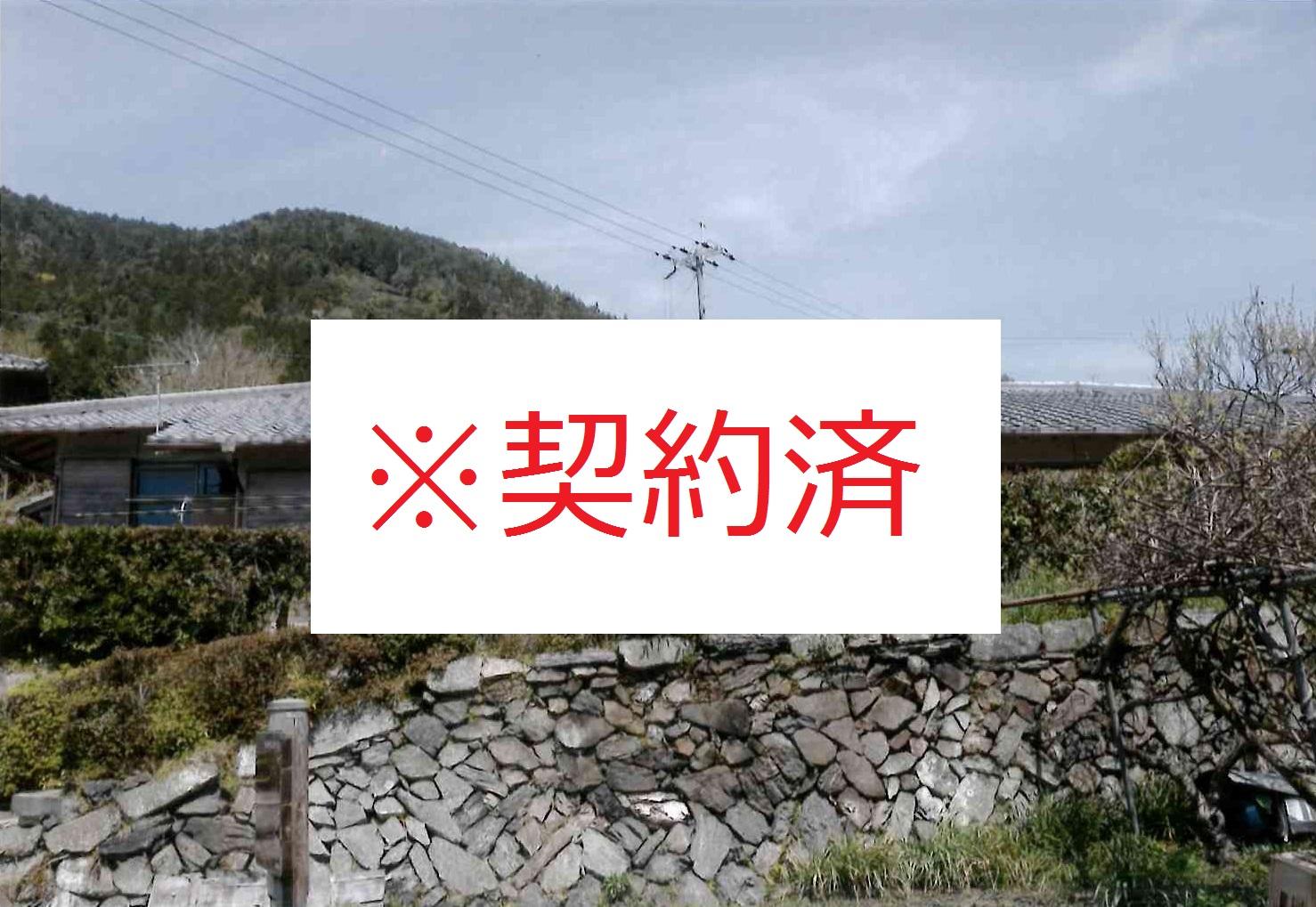 石垣の上に建てられた家の写真の中心に赤い文字で契約済みと記載されている写真