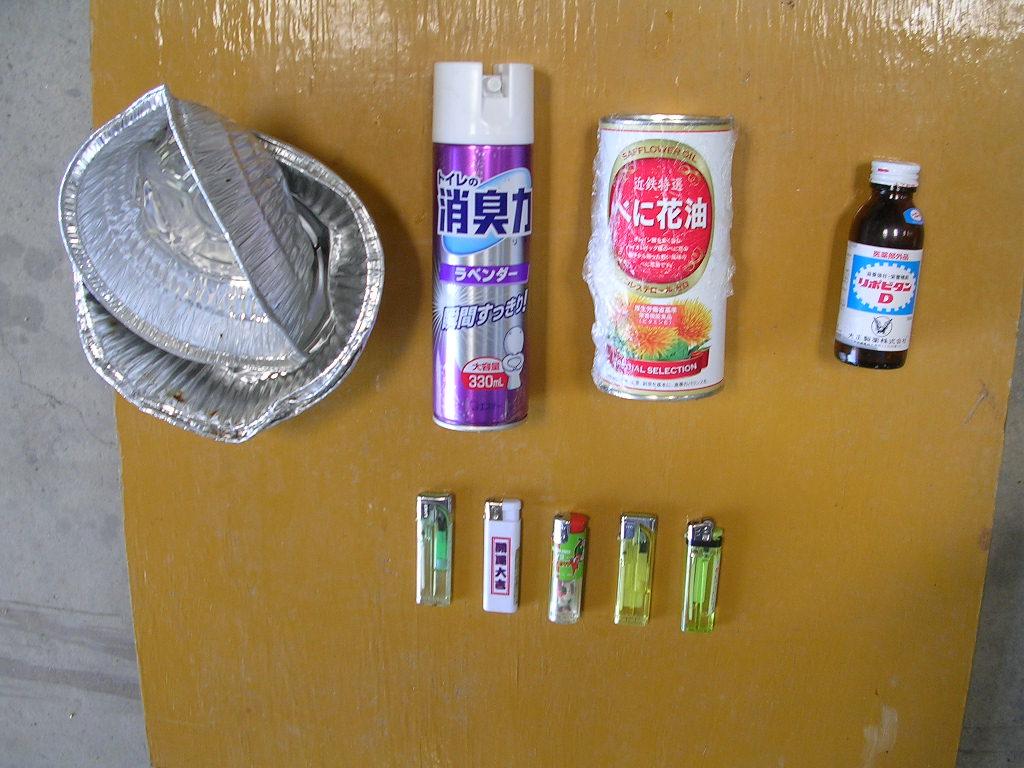 アルミホイル、ライター、空き瓶、スプレー缶が地面に並べて置かれてある写真