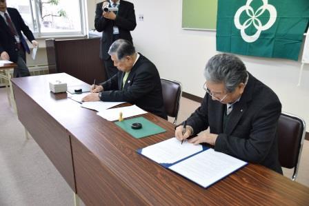 町長と吉田会長が協定書に署名をしている写真