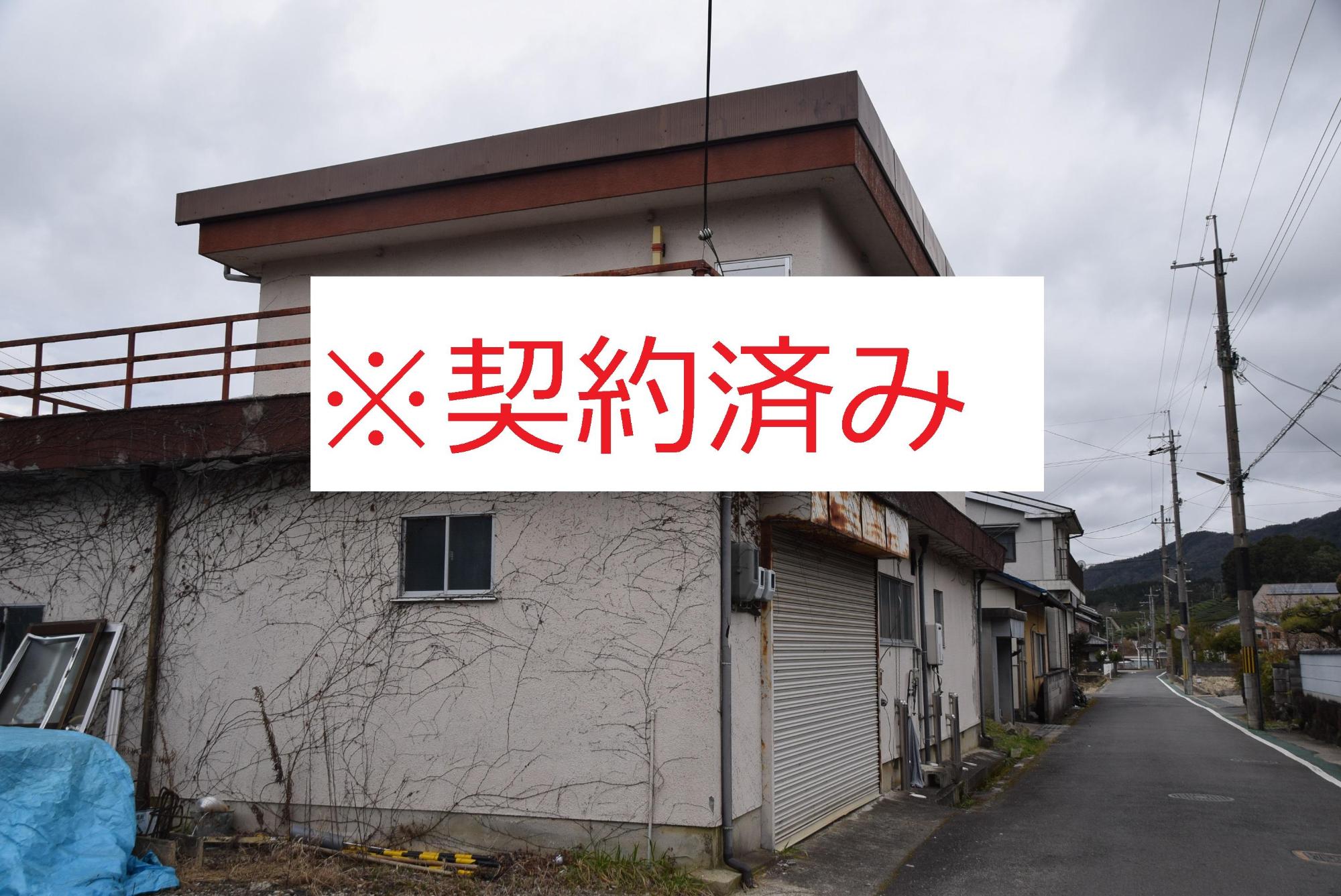 蔦が這った家の写真の中心に赤い文字で契約済みと記載されている写真