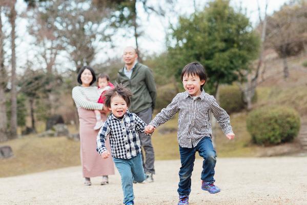 走る男の子とそれを見守る親たちの写真